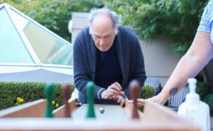 senior man playing table bowling outside with a friend
