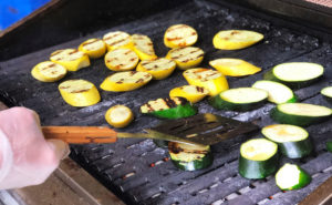 chef grilling zucchini on a barbecue