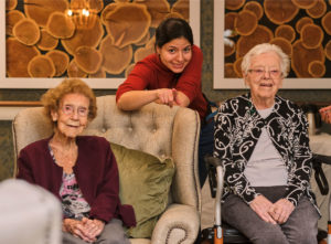 smiling nurse spending time with seniors at care home