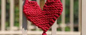 red woven heart hung on fence outside