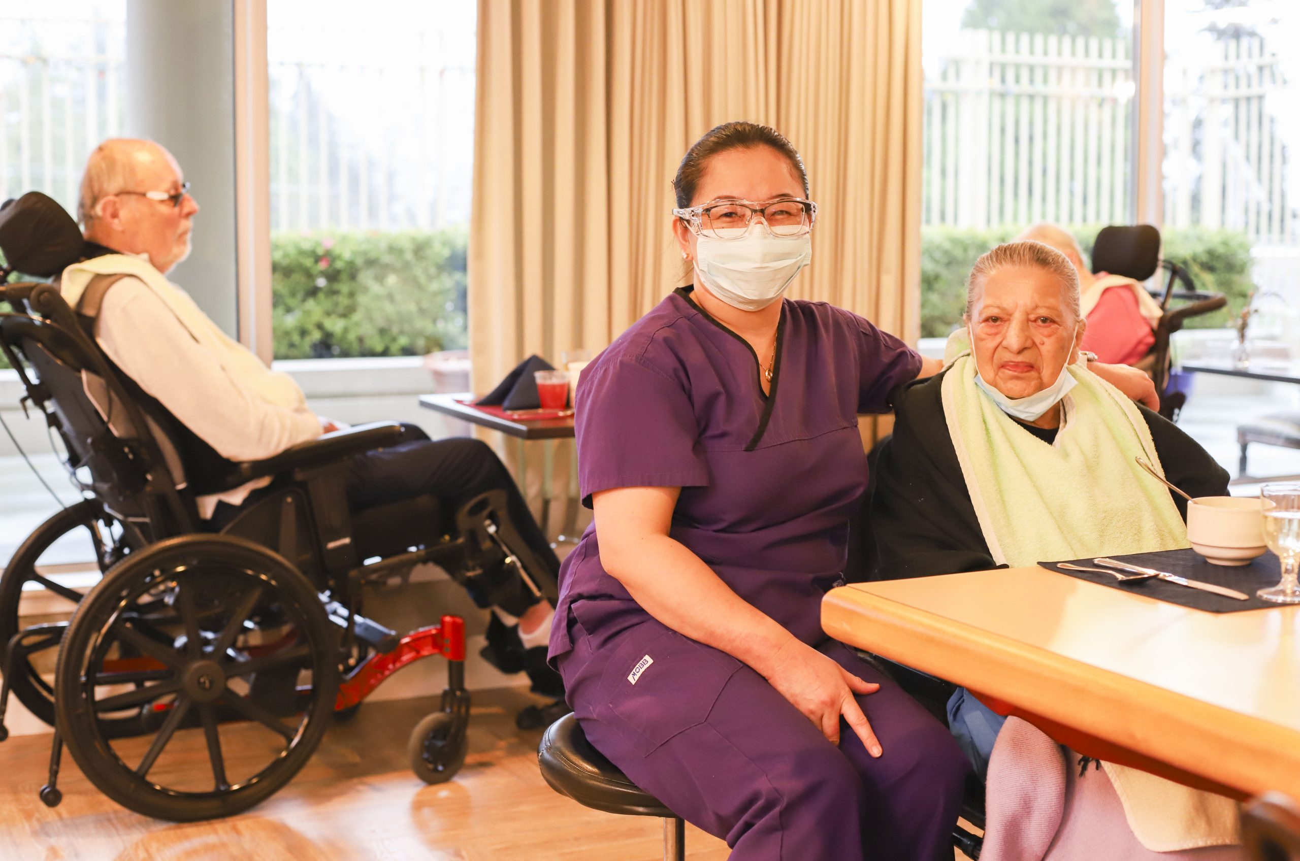nurse provides care to senior woman eating food at care home