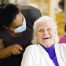an old lady smiling happily receiving personal care services from a nurse