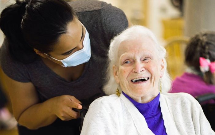 an old lady smiling happily receiving personal care services from a nurse