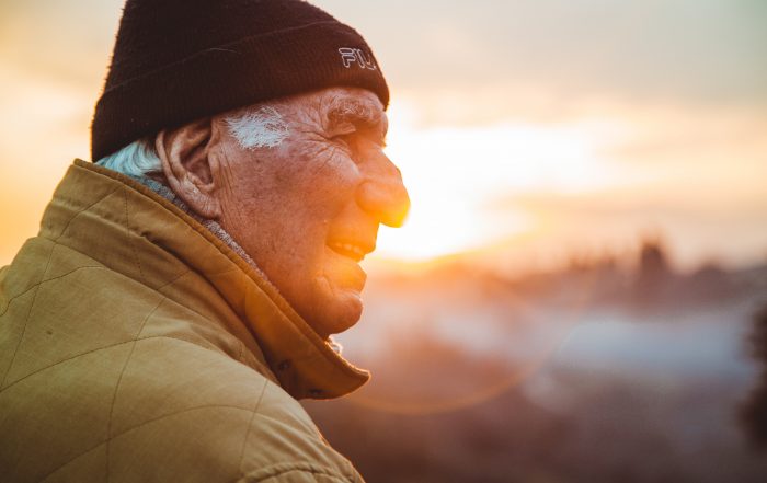 smiling senior man sitting outside watching the sunset