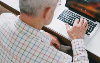 elderly man using laptop researching common scams for seniors