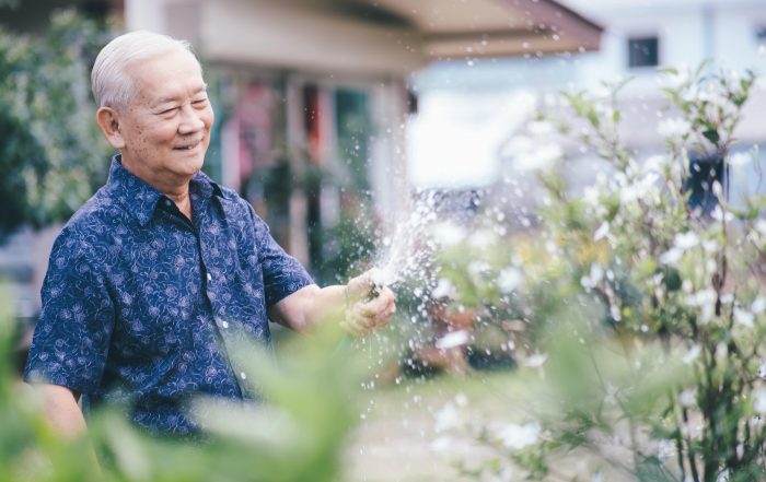 Happy senior man watering his garden in the summer